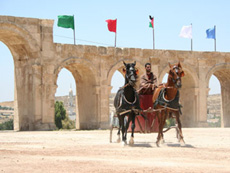 Triumphbogen in Jerash mit Fahnenauf der Empore und Streitwagen mit Fahrer im Vordergrund